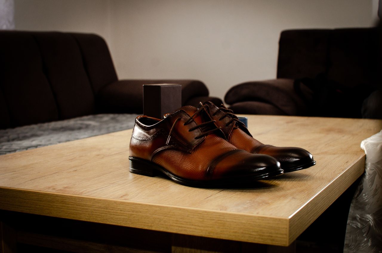 Stylish brown leather shoes placed on a wooden table in a cozy indoor setting.